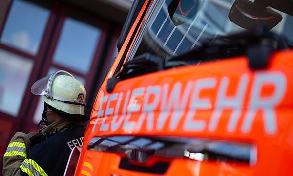 Feuerwehrmann steht neben einem Feuerwehrauto (Symbolbild)