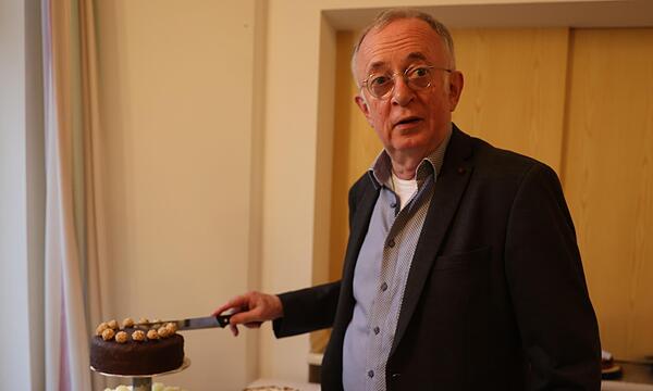 Pfarrer Hans Roppelt schneidet seine dreistöckige Geburtstagstorte höchstpersönlich an.