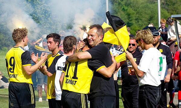 Erleichterung bei den Ködnitzer Spielern und Betreuern nach dem 0:0 gegen die SG Rugendorf/Losau, das zum Titelgewinn am vorletzten Spieltag reichte. Die Fans im Hintergrund feiern indes den Aufstieg in die Kreisliga mit Bengalos.