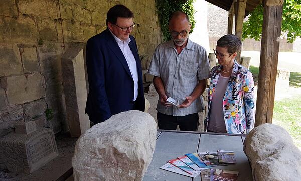 Kronachs 3. Bürgermeister Bernd Liebhardt, Bildhauer Tobias Schreiber und Tourismus-Chefin Kerstin Löw schmökern in allen Flyern der Sandstein-Werkstatt.