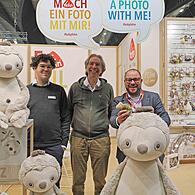 Landrat Sebastian Straubel (rechts) am Stand der Firma Fehn, mit Aron und Arnold Fehn sowie Faultieren und Chamäleons.