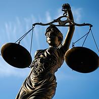 Eine Statue der Justitia hält eine Waage in der Hand.