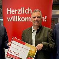 Beratungscenterleiter Wolfgang Kober (links) und Gebietsdirektor Heiko Därr (rechts) überreichen Bürgermeister Heiko Bäuerlein den symbolischen Spendencheck.