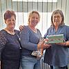 Gaby Hengstenberg (links) von Nadelzauber und Susanne Voll (rechts) übergeben Sonja Jacques vom Hospizverein einen sogenannten Leseknochen und eine Box mit der Spende.
