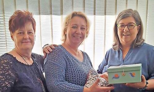 Gaby Hengstenberg (links) von Nadelzauber und Susanne Voll (rechts) übergeben Sonja Jacques vom Hospizverein einen sogenannten Leseknochen und eine Box mit der Spende.