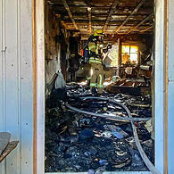 Eine Feuerwehr-Einsatzkraft steht in dem völlig ausgebrannten Wohnzimmer der Familie Pertsch in Untersiemau.