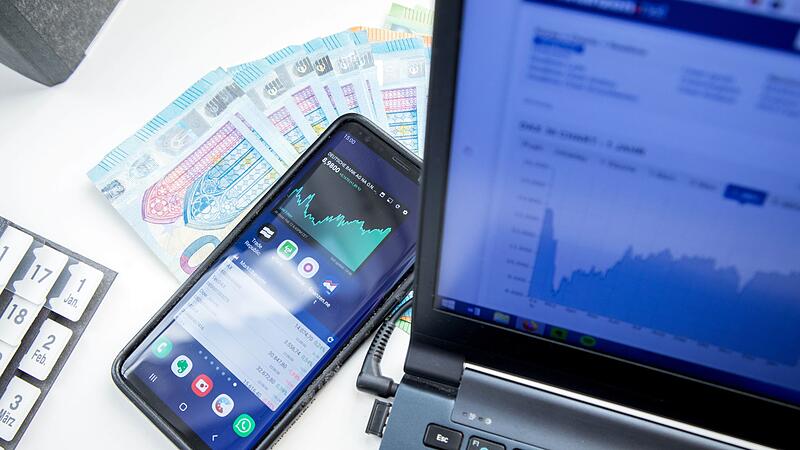 Smartphone, Laptop und Geldscheine auf einem Schreibtisch