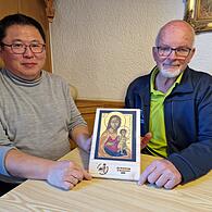Diakon Kim Sell und Heribert Vogler (Vertreter des Arbeitskreises Maria Ehrenberg) präsentieren die Ikone des Maria Ehrenbergs, die in diesem Jahr den Zelebranten als Gastgeschenk mitgegeben wird.