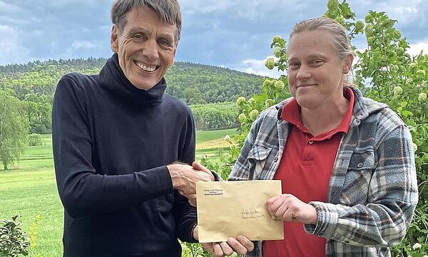 Pfarrerin Sonja von Aschen überreicht Burghard Schunkert einen Scheck mit den gesammelten Spendengeldern.