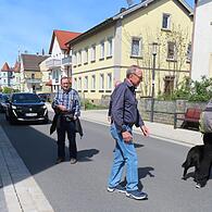 Die dunkelgrauen Längsrillen auf der linken Seite am Gehsteig zeigen eine Querungsmöglichkeit an - Die Gruppe überquert die Bahnhofstraße in Höhe des Optikers.