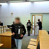 Der Angeklagte wird von zwei Polizeibeamten in den Gerichtssaal geführt.
