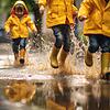 Kinder spielen mit Gummistiefeln im Regen
